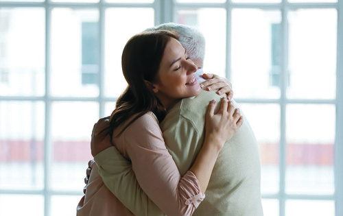 Grownup daughter straining to heart dear senior dad meeting after long time separation. Tender young woman adult grandkid cuddling with warmth elderly man grandfather greeting with birthday father day